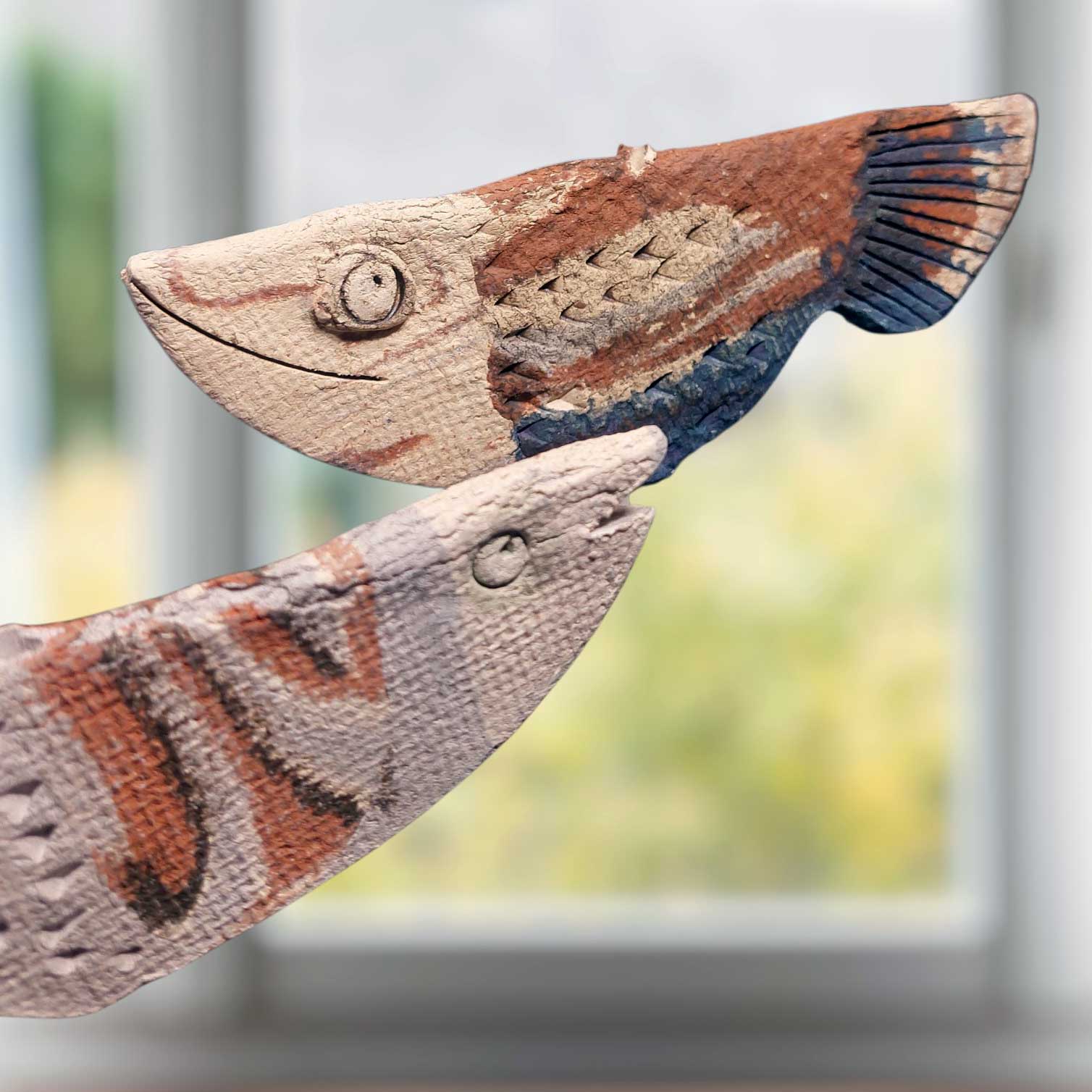 Zwei handgefertigte Keramik-Fische in maritimer Optik mit strukturierter Oberfläche als dekoratives Windspiel oder Aufsteller für ein maritimes Zuhause.
