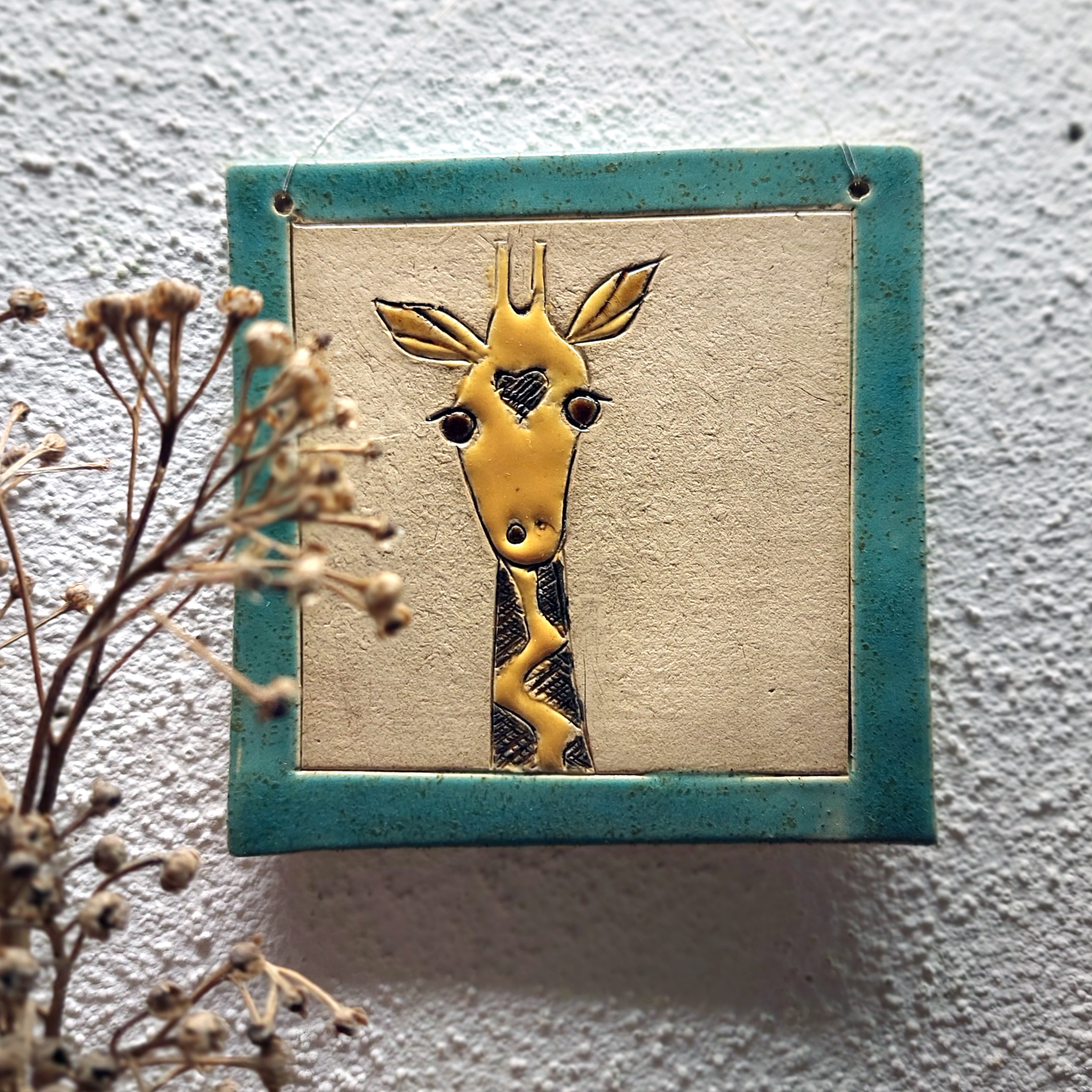 Quadratische Keramikfliese mit handgezeichnetem Giraffenmotiv in Gelb und Blau, ideal als dekoratives Wandbild für ein liebevolles Zuhause.
