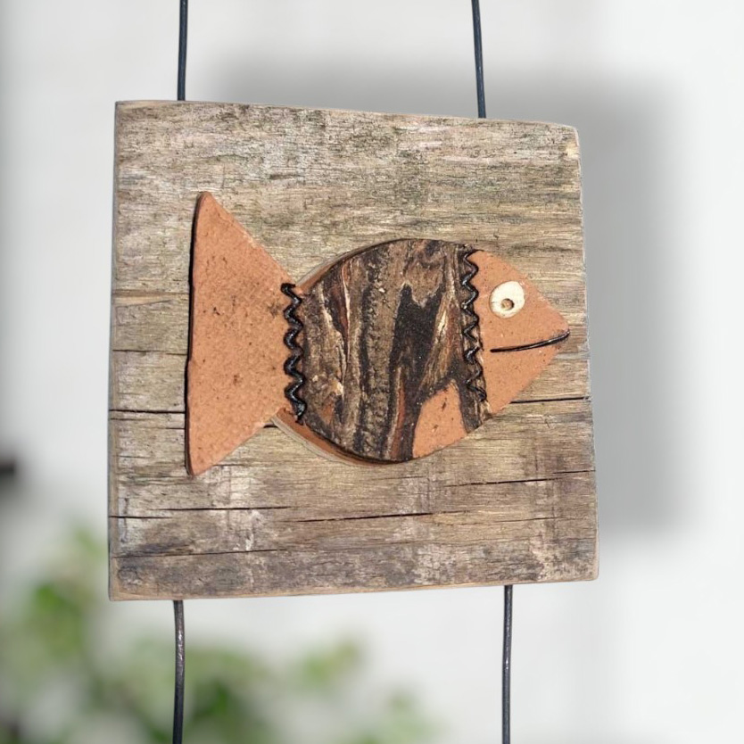 Hängende Wanddekoration mit einem Fisch aus Keramik auf rustikalem Altholz, ideal als maritime Wohndekoration für ein gemütliches Zuhause.